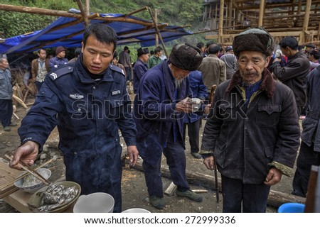 Langde Village, Guizhou, China - April 16, 2010: Chinese police at village celebration eat using chopsticks.