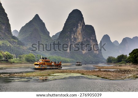 Yangshuo, Guangxi, China - March 29, 2010: Cruise ship packed with tourists travels the magnificent scenic route along the Lijiang River from Guilin to Yangshou. southern China.