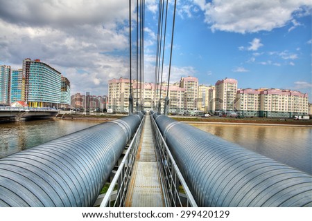 St. Petersburg, Russia - July 9, 2015: Heating main in a residential area, the steel pipeline crosses the river on a cable-stayed bridge.