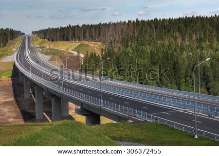 Saint Petersburg, Russia - August 7, 2015: Four-speed road through the forest, and a steel motor road bridge on reinforced concrete piers, Priozersk district, Leningrad region, highway Sortavala.