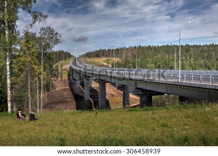 Saint Petersburg, Russia - August 7, 2015: The new steel bridge on concrete pillars crossing bed of forest stream, a modern four-lane highway St. Petersburg - Sortavala, passes through a dense forest.