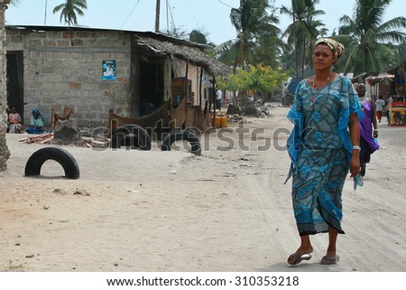 Zanzibar, Tanzania - February 18, 2008: African woman walking along the dusty road of the coastal fishing village.