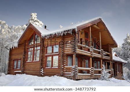 Log cabin with large windows, balcony and porch, modern house design, snowy winter, sunny day.