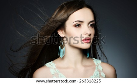 Portrait of a beautiful brunette young woman with long windy hair and with earrings