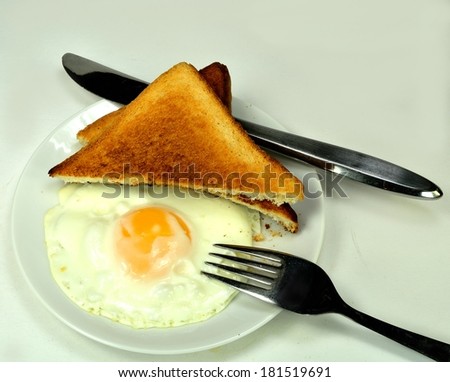 Fried egg with toast and a knife and fork.