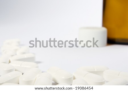 A border of pills on the left-hand side and lower part of a white frame with an opend bottle in the top right-hand area