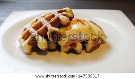 Beautiful ham cheese eggs benedict and a rich hollandaise sauce on waffle