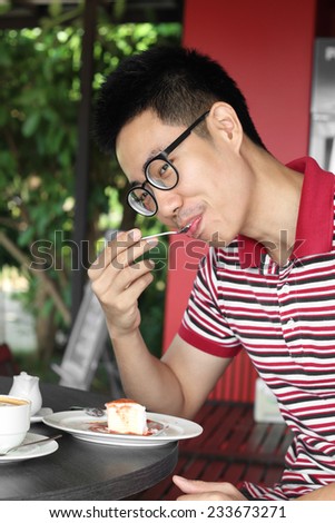 Young asian man eating a cake