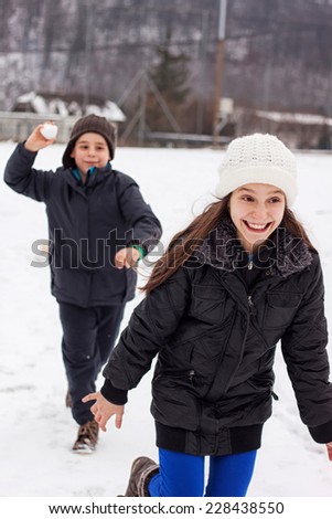 boy throw snow ball to the running girl