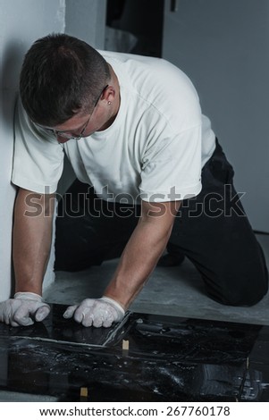 handyman pushing granite plates to laying floor with stone plates