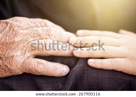 nephew touching grandfather\'s hand in sunlight