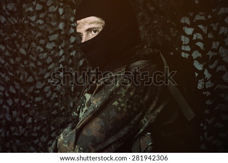 camouflage army soldier with dirty face and balaclava looking sideways