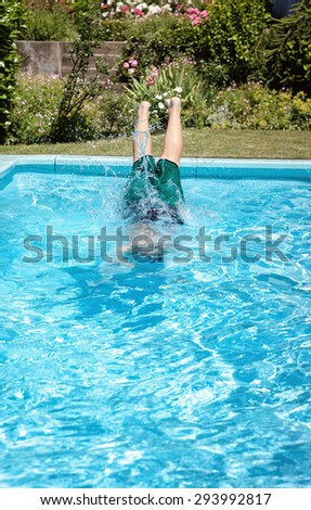 feet of young boy jumping into the pool in front of green plants
