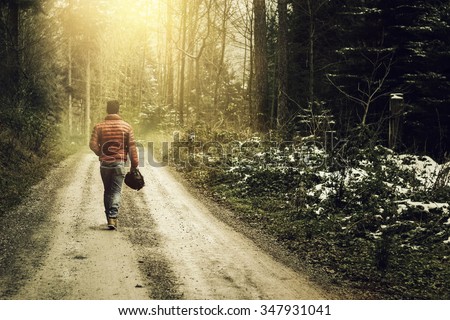 Nature footpath through snowy forest and walking alone man against fog and sunshine