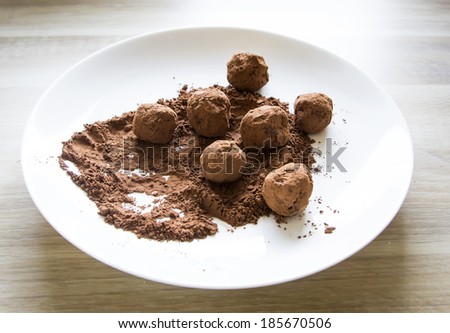 homemade chocolate truffles in cocoa powder on white plate