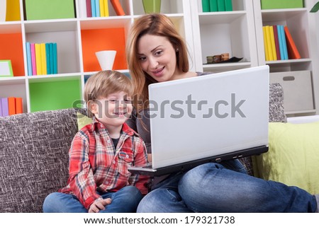 Happy mother and son using computer on the couch