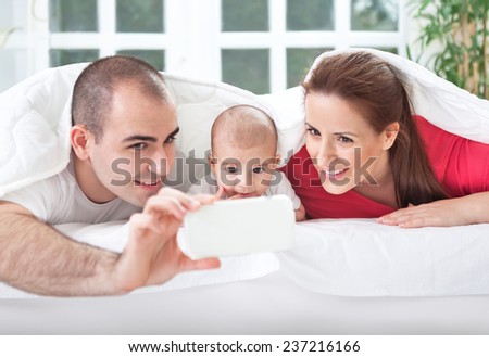 Happy smiling family taking picture of themselves on bed