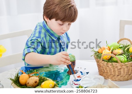 The day before Easter, beautiful child painting eggs for easter