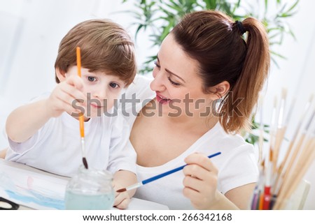 Young beautiful mother learn her child how to paint