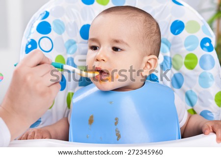 Feeding hungry baby child in chair