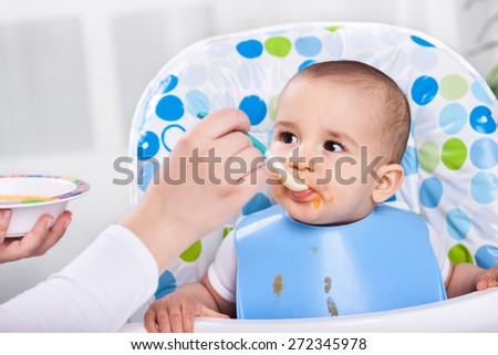 Adorable hugry baby child likes to eat in the kitchen