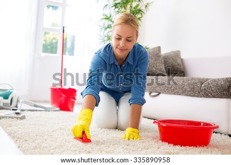 Attractive housewife cleaning carpet with brush and doing housework