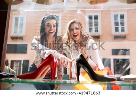 Two surpriced girl showing on elegant shoes, shopping time