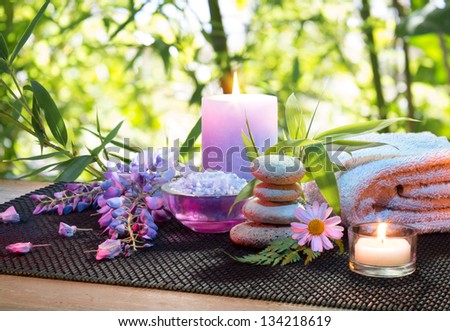 massage in the bamboo garden with violet flowers, candles and towel