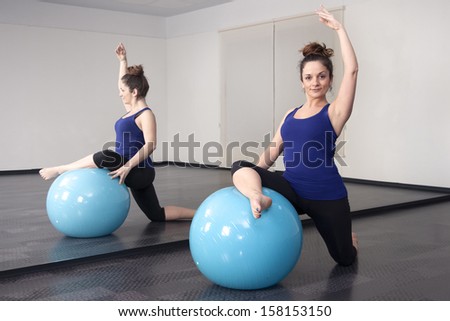 woman doing pilates ball on the floor in the mirror
