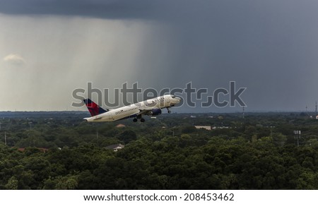 Tampa, Florida July 10th, 2014. Tampa International Airport is a popular destination for many travelers. A Delta aircraft takes off with a thunderstorm and rain in the background.