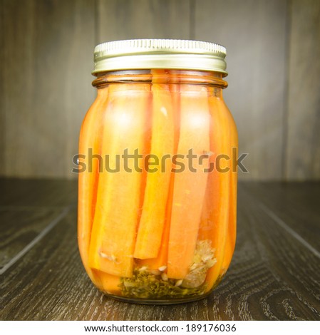 A jar of pickled carrots on a wood table