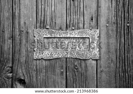 Mail slot mounted on rough wooden plank door