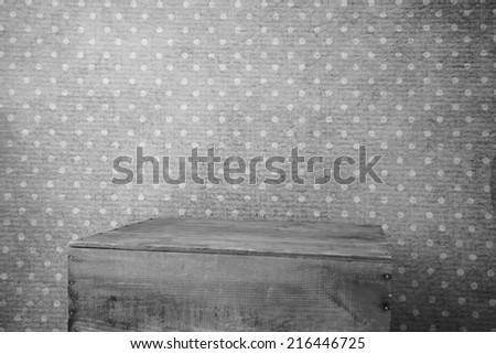 Wood box in front of an old wallpapered wall black and white