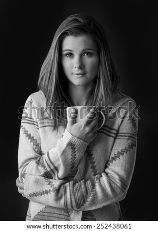 Portrait of a young woman in a comfy sweater isolated on black in black and white