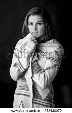 Portrait of a young woman in a comfy sweater isolated on black in black and white