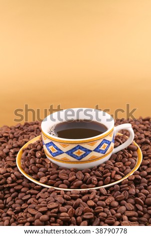 Cup of black coffee and lot of coffee beans on gold background