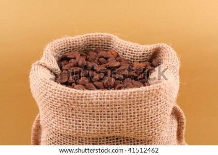 Grains of coffee and coffee canvas bag on gold background