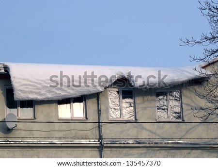The snow canopy which is dangerously hanging down from a roof