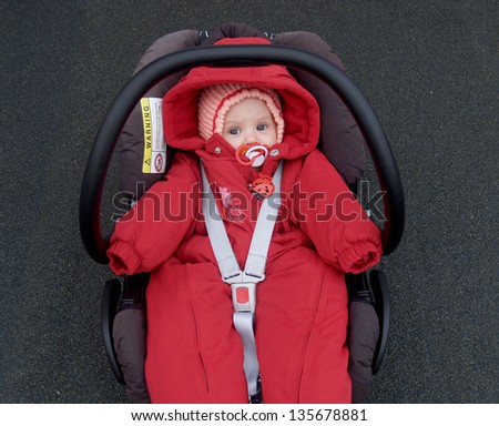 The baby lies in a children\'s car seat