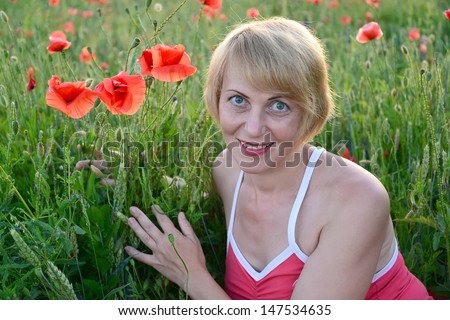 Portrait of the woman of average years with red poppies