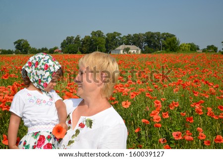 The grandmother and the granddaughter look at each other in the middle of a poppy field
