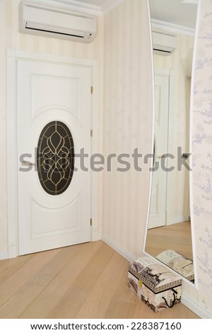Fragment of an interior of a living room with a white door and a stained-glass window. Modern classics with rococo elements