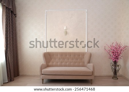 Fragment of an interior of a hotel room with a sofa and a decorative bouquet of an Oriental cherry in a floor vase