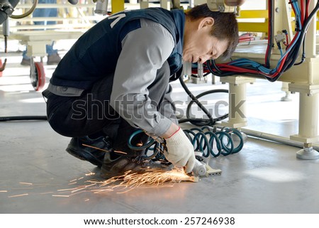 KALININGRAD, RUSSIA â?? SEPTEMBER 16, 2014: The worker cuts off a metal detail by means of a hand circular saw. Automobile plant