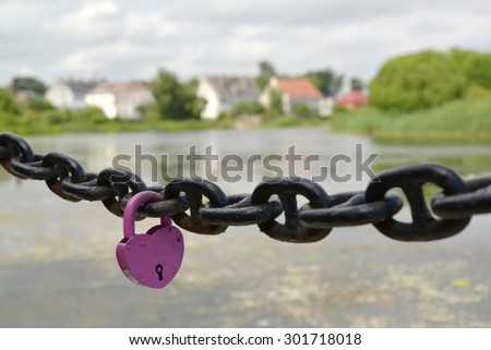 The lilac lock hangs on a chain against the river. Kaliningrad region
