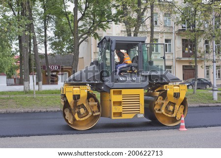 PSKOV, RUSSIA - JUNE 22, 2014: Yellow roller making road repairs