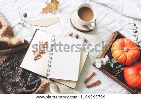 Autumn breakfast in bed composition. Card, notebook mockup. Cup of coffee, eucalyptus leaves, pumpkins on wooden tray. White linen background. Thanksgiving, halloween concept. Flat  lay, top view.