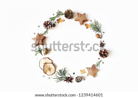 Christmas circle floral composition. Wreath of cypress branches, pine cones, anise, confetti stars, dry apples and hydrangea flowers on white background. Winter wedding design. Flat lay, top view.