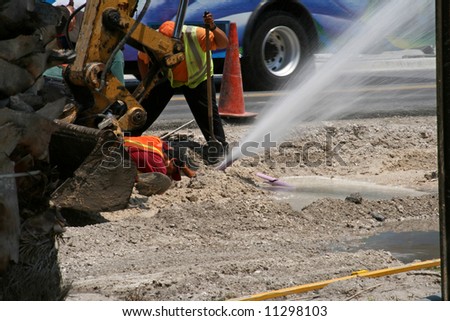 construction worker digging up the road strikes a water pipe
