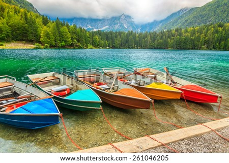 Cloudy sky,colorful boats on the alpine lake near Slovenian-Italy border,Lake Fusine,Italy